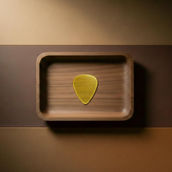 Vintage amber-colored PEI (Ultem) guitar pick with high durability and translucency in a wooden case.