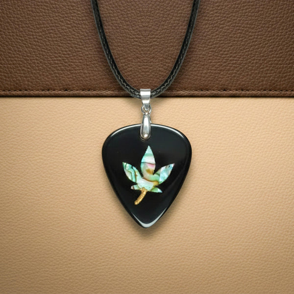 Black guitar pick pendant featuring an iridescent abalone shell inlay shaped like a hemp leaf. Edgy, rock-style jewelry for guitar players.