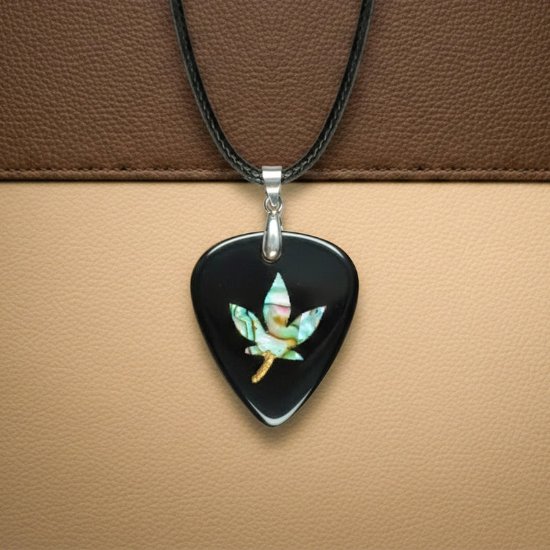 Black guitar pick pendant featuring an iridescent abalone shell inlay shaped like a hemp leaf. Edgy, rock-style jewelry for guitar players.