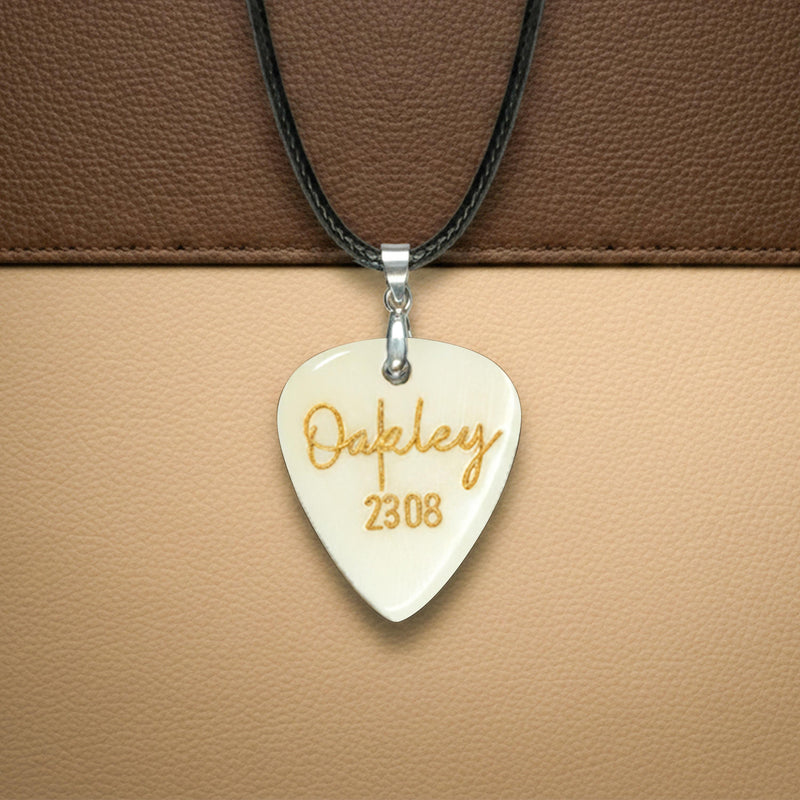 Hand-carved white bone guitar pick necklace with gold "Oakley 2308" custom engraving.