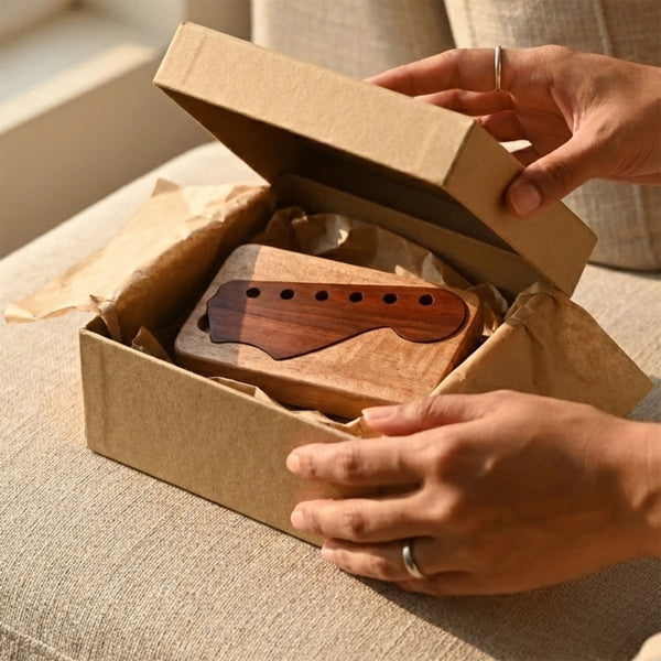 Unboxing a custom wooden guitar pick case with headstock-shaped lid, wrapped in kraft paper gift packaging