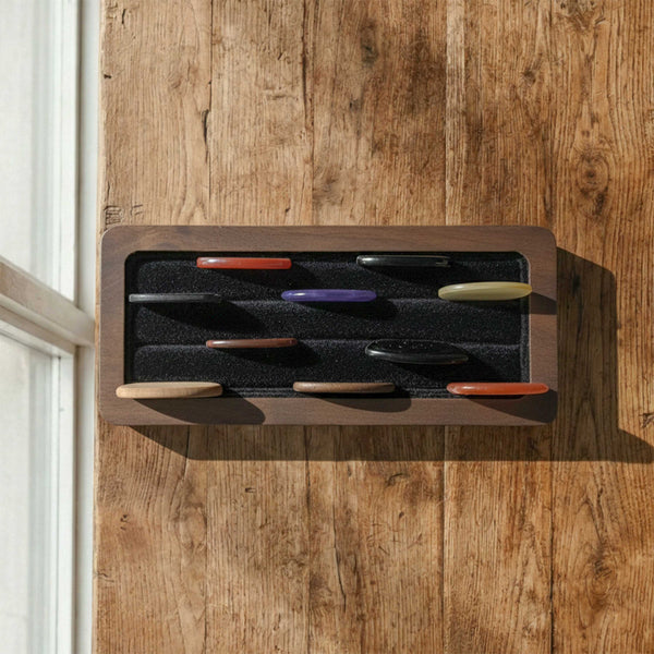 Rectangular wooden display tray for guitar picks. Features a black foam insert with horizontal rows to organize and display multiple picks upright on a desk.