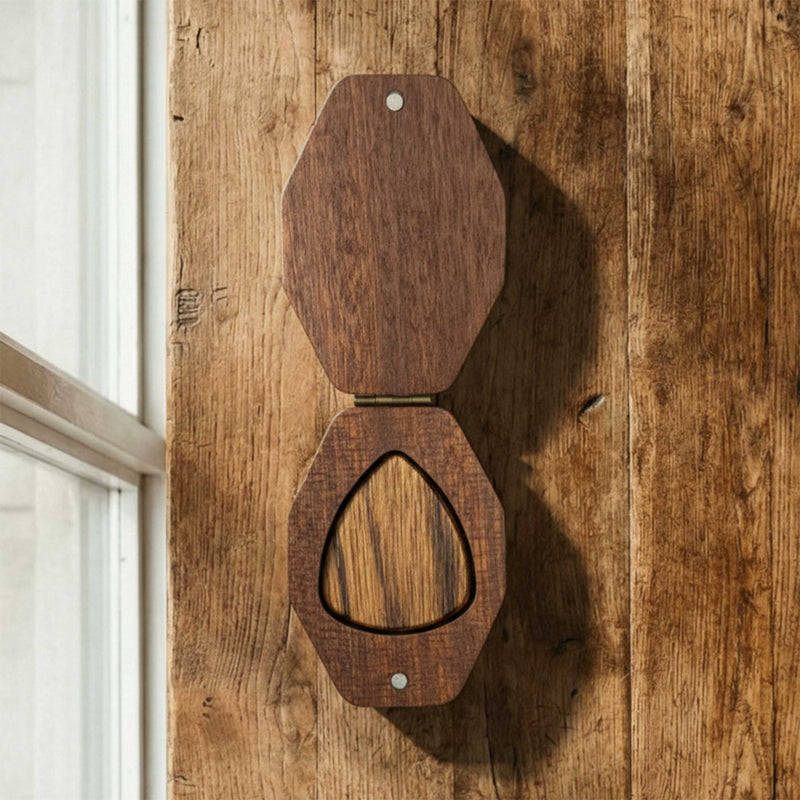 Hexagonal wooden guitar pick box with a brass hinge. Open case displays a single wooden pick inside, featuring a modern geometric design.