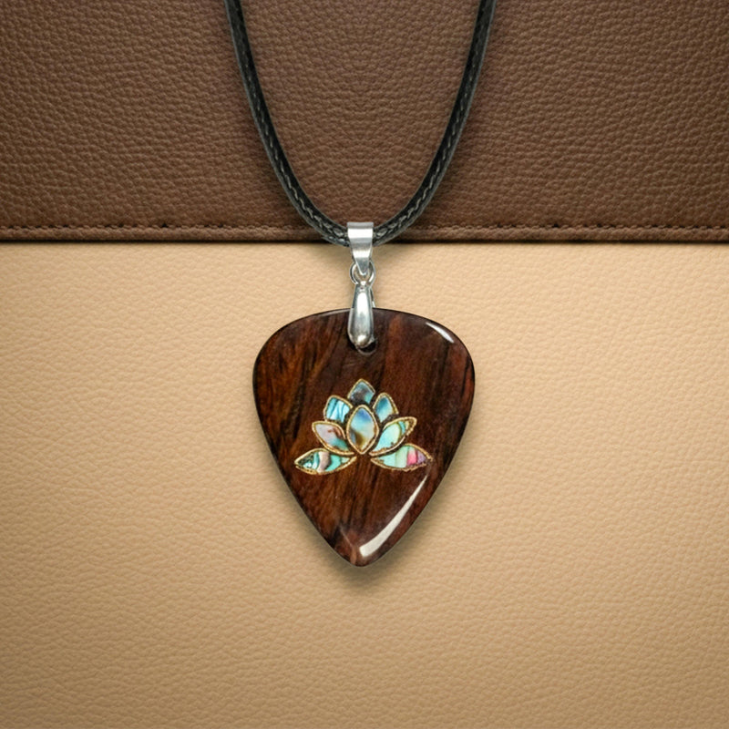 Wooden guitar pick necklace with a detailed abalone shell lotus flower inlay. Zen-inspired musical accessory on a leather cord.