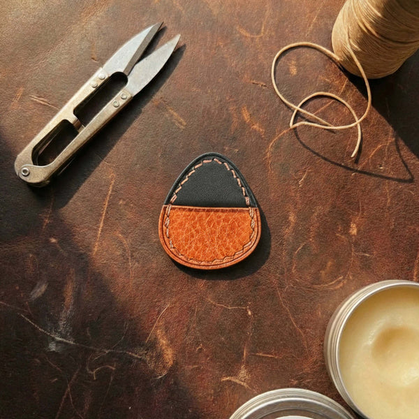 Premium leather guitar pick pocket with black flap and textured brown body.