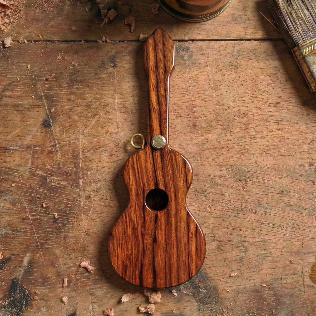 Guitar-shaped wooden pick box made of rosewood with a lanyard loop and brass knob, designed as a musical instrument accessory gift.