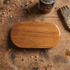 Oval shaped wooden pill box or guitar pick case, smooth polished finish with linear wood grain, minimalist musician accessory.