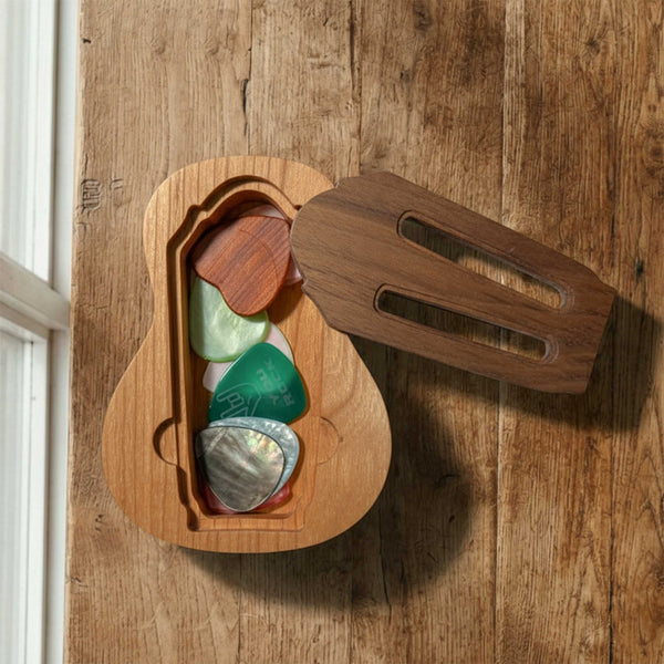 Large wooden pick holder shaped like an acoustic guitar body. Features a distinct lid designed like a guitar bridge, covering a compartment for multiple picks.
