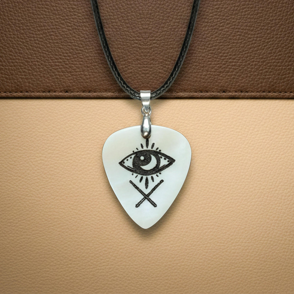 White bone guitar pick necklace engraved with a mystic eye and crossed lines symbol.