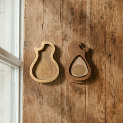 Organic guitar-body shaped wooden pick case with a pivoting cover. Features contrasting light and dark wood tones, open to reveal storage for a guitar pick.