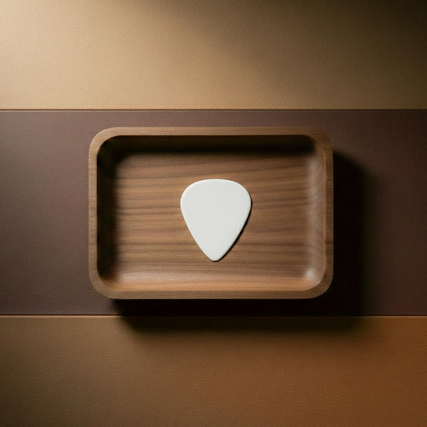 Polished white agate stone guitar pick resting on a wooden surface.